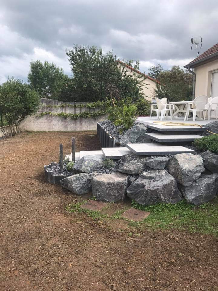 Jardin en travaux : terre à nu, enrochement et marches en dalles vers la terrasse